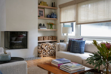 Cette photo montre un petit salon ouvert avec un mur blanc, un sol en bois brun, une cheminée d'angle, un manteau de cheminée en plâtre, un téléviseur encastré et un sol marron.