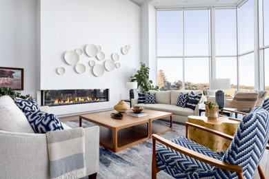 Huge beach style open concept medium tone wood floor, brown floor and vaulted ceiling living room photo in Other with white walls and a ribbon fireplace