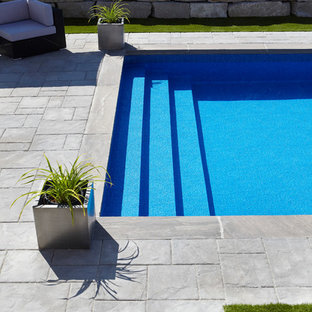 Bild på en stor funkis rektangulär baddamm på baksidan av huset, med marksten i tegel