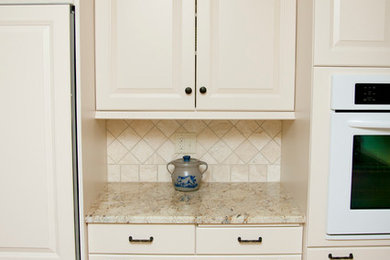 Mid-sized elegant u-shaped medium tone wood floor eat-in kitchen photo in Milwaukee with a double-bowl sink, raised-panel cabinets, white cabinets, granite countertops, beige backsplash, stone tile backsplash, stainless steel appliances and a peninsula