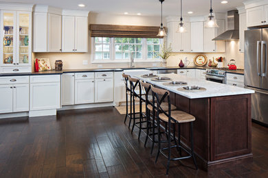 Large transitional l-shaped eat-in kitchen in New York with a farmhouse sink, white cabinets, brown splashback, stainless steel appliances, dark hardwood floors, with island, brown floor, stone tile splashback, shaker cabinets, marble benchtops and white benchtop.