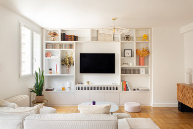 Idée de décoration pour un grand salon beige et blanc minimaliste avec une bibliothèque ou un coin lecture, un mur beige, parquet clair, aucune cheminée et un téléviseur fixé au mur.