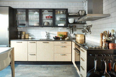 Photo of a mid-sized scandinavian l-shaped eat-in kitchen in Stockholm with a drop-in sink, flat-panel cabinets, light wood cabinets, white splashback, subway tile splashback, stainless steel appliances, concrete floors and no island.