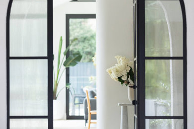 Réalisation d'un hall d'entrée design avec un mur blanc, parquet clair, une porte simple et une porte en verre.