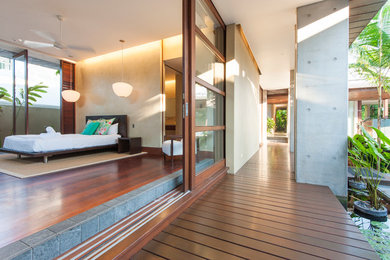 Design ideas for an expansive tropical master bedroom in Cairns with yellow walls and dark hardwood floors.