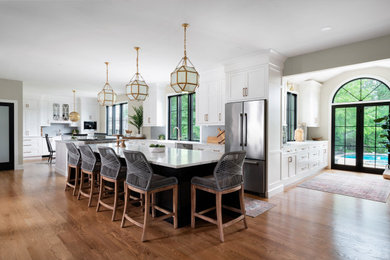Example of a transitional light wood floor kitchen design in Philadelphia with a farmhouse sink, white cabinets, gray backsplash, porcelain backsplash, stainless steel appliances, an island and white countertops