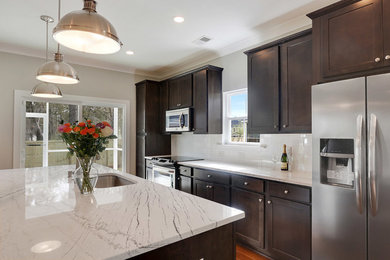 Transitional single-wall medium tone wood floor kitchen photo in Charleston with a single-bowl sink, shaker cabinets, dark wood cabinets, granite countertops, white backsplash, subway tile backsplash, stainless steel appliances and an island