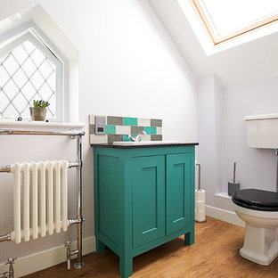 Exemple d'un WC et toilettes rétro avec un placard à porte shaker, des portes de placard turquoises, un WC séparé, un mur gris, un sol en bois brun, un plan vasque et un sol marron.