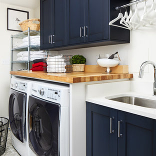 Inspiration for a traditional single-wall separated utility room in DC Metro with a submerged sink, shaker cabinets, blue cabinets, wood worktops, white walls, a side by side washer and dryer, grey floors and white worktops.