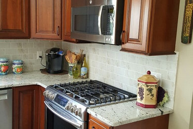 Example of a mid-sized classic l-shaped ceramic tile kitchen design in Philadelphia with an undermount sink, raised-panel cabinets, dark wood cabinets, granite countertops, white backsplash, stone tile backsplash, stainless steel appliances and an island