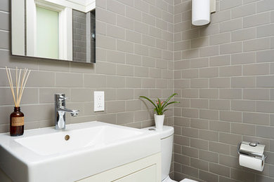 Inspiration for a transitional powder room in Minneapolis with flat-panel cabinets, a two-piece toilet, gray tile, subway tile, beige cabinets and white floor.