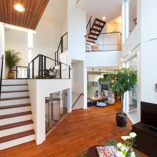 Inspiration för ett funkis allrum med öppen planlösning, med vita väggar, mellanmörkt trägolv, en fristående TV och brunt golv