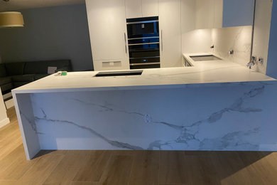 Large minimalist u-shaped porcelain tile and gray floor eat-in kitchen photo in Cincinnati with an undermount sink, flat-panel cabinets, white cabinets, quartz countertops, quartz backsplash, stainless steel appliances, an island, multicolored backsplash and multicolored countertops
