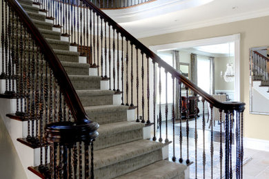 Large traditional carpeted u-shaped staircase in Philadelphia with wood risers and mixed railing.