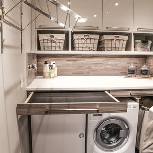 Design ideas for a medium sized traditional utility room in Calgary with flat-panel cabinets, grey cabinets, engineered stone countertops, beige walls, slate flooring and a side by side washer and dryer.