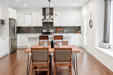Example of a transitional l-shaped medium tone wood floor eat-in kitchen design in Toronto with shaker cabinets, white cabinets, gray backsplash, stainless steel appliances, an island, white countertops and slate backsplash