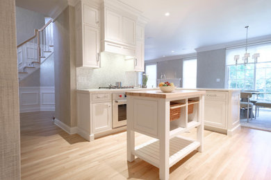 Inspiration for a mid-sized transitional l-shaped light wood floor and brown floor open concept kitchen remodel in New York with an undermount sink, beaded inset cabinets, white cabinets, quartz countertops, white backsplash, porcelain backsplash, stainless steel appliances and an island