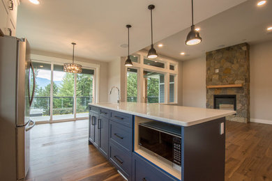 Eat-in kitchen - large transitional u-shaped medium tone wood floor and brown floor eat-in kitchen idea in Vancouver with an undermount sink, recessed-panel cabinets, white cabinets, quartz countertops, white backsplash, subway tile backsplash, stainless steel appliances, an island and white countertops