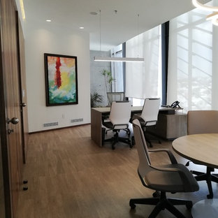 This is an example of a large modern study in Other with white walls, vinyl flooring, a freestanding desk and brown floors.