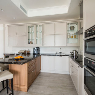 Новые идеи обустройства дома: большая п-образная кухня - столовая в стиле современная классика с врезной раковиной, серыми фасадами, мраморной столешницей, серым фартуком, фартуком из каменной плитки, техникой из нержавеющей стали, полом из керамогранита, полуостровом, бежевым полом и фасадами с утопленной филенкой