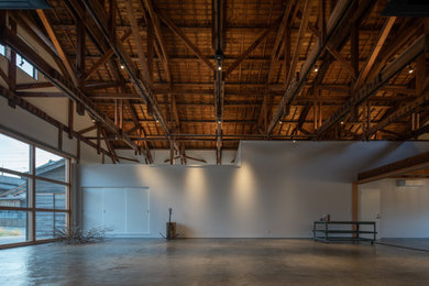 Ejemplo de estudio industrial de tamaño medio con paredes blancas, suelo de cemento, suelo gris y vigas vistas