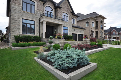 This is an example of a mid-sized traditional full sun front yard concrete paver landscaping in Toronto.
