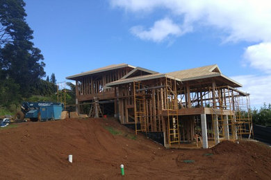 Photo of a two floor house exterior in Hawaii with wood cladding and a hip roof.