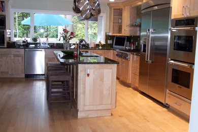 Inspiration for a contemporary l-shaped light wood floor eat-in kitchen remodel in New York with an undermount sink, shaker cabinets, light wood cabinets, granite countertops, stainless steel appliances, an island, black backsplash and subway tile backsplash