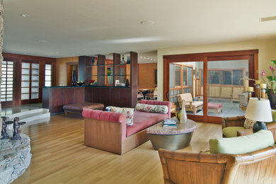 Mid-sized island style open concept bamboo floor living room library photo in San Diego with beige walls, a standard fireplace, a stone fireplace and no tv