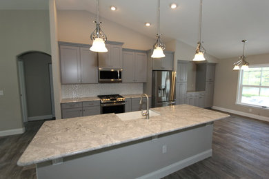 Inspiration for a mid-sized transitional galley porcelain tile and gray floor open concept kitchen remodel in Orlando with a farmhouse sink, recessed-panel cabinets, gray cabinets, gray backsplash, mosaic tile backsplash, stainless steel appliances, an island, gray countertops and quartz countertops
