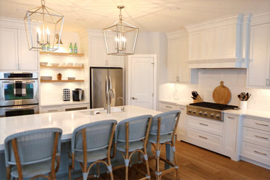 Inspiration for a large craftsman l-shaped light wood floor and brown floor eat-in kitchen remodel in Minneapolis with an undermount sink, white cabinets, quartzite countertops, white backsplash, ceramic backsplash, stainless steel appliances, an island, white countertops and recessed-panel cabinets