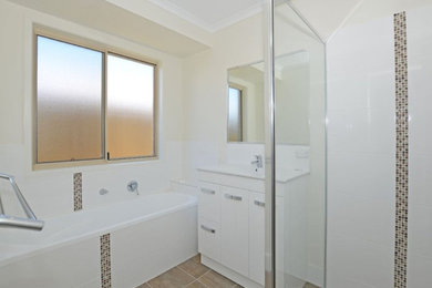 Modern bathroom in Brisbane with white cabinets, a corner shower, a drop-in sink and granite benchtops.