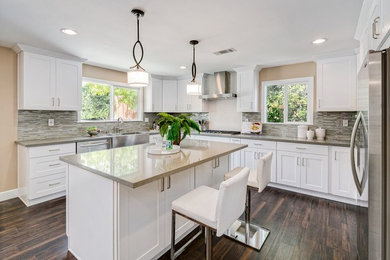 Kitchen - transitional l-shaped dark wood floor kitchen idea in Miami with a farmhouse sink, shaker cabinets, white cabinets, multicolored backsplash, matchstick tile backsplash, stainless steel appliances and an island
