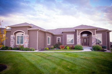 Example of a large classic red one-story stone exterior home design in Kansas City with a clipped gable roof