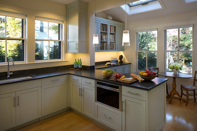 Example of a mid-sized transitional u-shaped light wood floor eat-in kitchen design in Boston with an undermount sink, shaker cabinets, blue cabinets, granite countertops, white backsplash, ceramic backsplash, a peninsula and stainless steel appliances