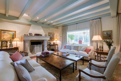 This is an example of a large traditional formal enclosed living room in Madrid with white walls, a standard fireplace, a brick fireplace surround and no tv.