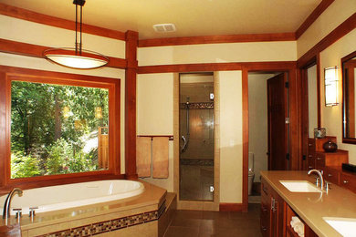 This is an example of a mid-sized arts and crafts master bathroom in Sacramento with flat-panel cabinets, medium wood cabinets, a freestanding tub, a corner shower, a two-piece toilet, beige tile, ceramic tile, beige walls, ceramic floors, an undermount sink, engineered quartz benchtops, brown floor and a hinged shower door.