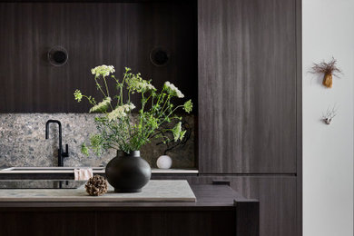 Example of a small minimalist galley light wood floor and brown floor eat-in kitchen design in Atlanta with a single-bowl sink, flat-panel cabinets, black cabinets, quartz countertops, gray backsplash, quartz backsplash, paneled appliances, an island and gray countertops