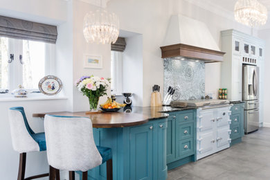 Large classic single-wall open plan kitchen in Other with a built-in sink, recessed-panel cabinets, blue cabinets, granite worktops, coloured appliances, ceramic flooring, black worktops, blue splashback, glass sheet splashback and grey floors.