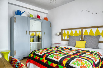 Example of a mid-sized eclectic master medium tone wood floor bedroom design in Other with white walls and no fireplace