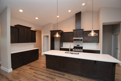 Example of a mid-sized transitional l-shaped dark wood floor and brown floor open concept kitchen design in Portland with an undermount sink, shaker cabinets, dark wood cabinets, quartz countertops, white backsplash, subway tile backsplash, stainless steel appliances and an island