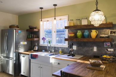 Inspiration for a mid-sized eclectic l-shaped eat-in kitchen in Sacramento with a farmhouse sink, shaker cabinets, white cabinets, wood benchtops, grey splashback, cement tile splashback, stainless steel appliances, dark hardwood floors, a peninsula and brown floor.
