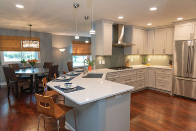 Eat-in kitchen - mid-sized transitional u-shaped dark wood floor and brown floor eat-in kitchen idea in Milwaukee with an undermount sink, shaker cabinets, white cabinets, quartz countertops, blue backsplash, glass tile backsplash, stainless steel appliances, a peninsula and white countertops