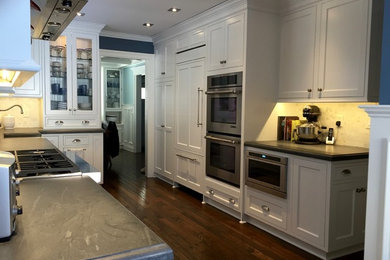 Traditional kitchen in New York with a farmhouse sink, beaded inset cabinets, white cabinets and stone tile splashback.