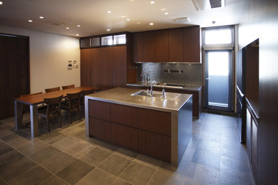 他の地域にあるおしゃれなキッチン (濃色木目調キャビネット、ステンレスカウンター、セラミックタイルの床、グレーの床) の写真