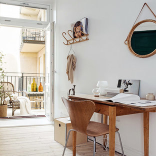 This is an example of a mid-sized scandinavian study room in Gothenburg with white walls, light hardwood floors, no fireplace and a freestanding desk.