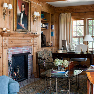 Inspiration för stora klassiska hemmabibliotek, med mellanmörkt trägolv, en standard öppen spis, en spiselkrans i tegelsten och ett fristående skrivbord