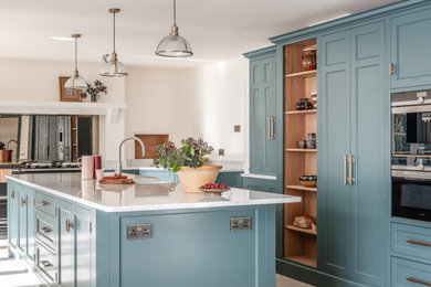Inspiration for a large traditional kitchen in Other with a single-bowl sink, blue cabinets, granite worktops, white splashback, granite splashback, black appliances, limestone flooring, an island, beige floors and white worktops.