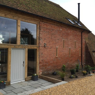 Новый формат декора квартиры: огромный, двухэтажный фасад дома красного цвета в стиле кантри с облицовкой из дерева и полувальмовой крышей