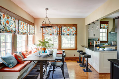 Example of a large arts and crafts u-shaped medium tone wood floor eat-in kitchen design in San Francisco with a farmhouse sink, shaker cabinets, white cabinets, soapstone countertops, blue backsplash, ceramic backsplash, stainless steel appliances and a peninsula